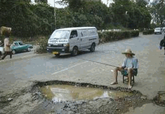 Man fishing in hole in road